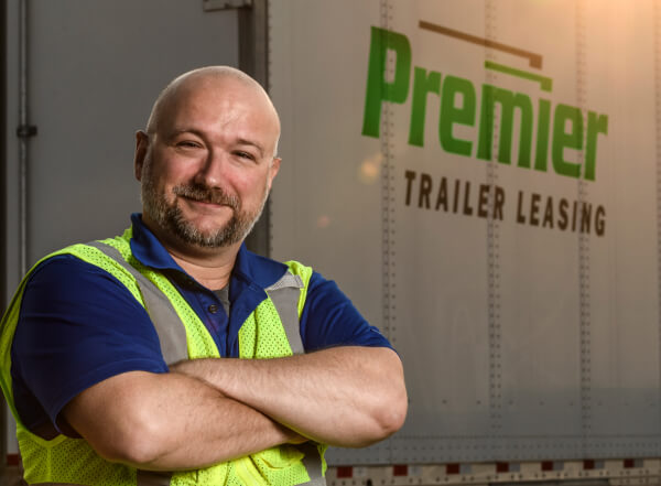 Happy Premier employee standing in front of a Premier truck